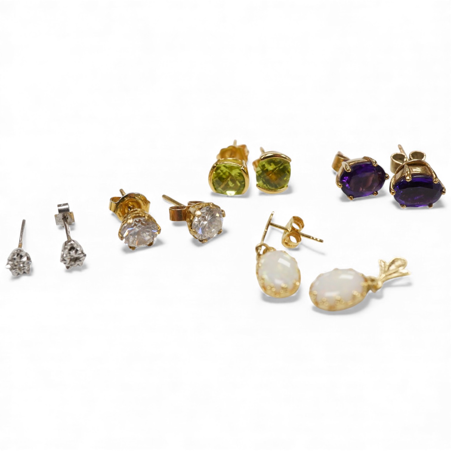 A pair of chequerboard cut peridot set 18ct stud earrings, a pair of amethyst set 9ct stud earrings and three costume pairs of earrings.